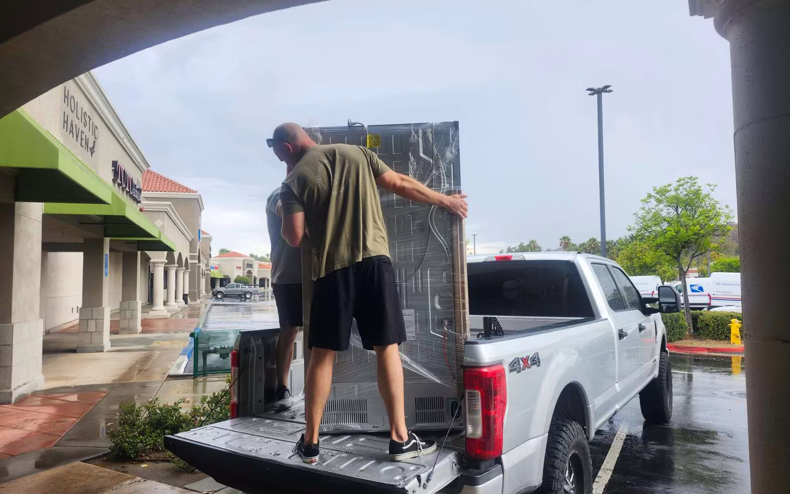 A refrigerator being loaded into a customer's pickup truck outside the store